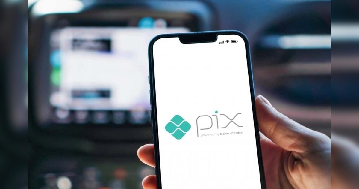 Pessoa fazendo transferência bancária via pix ao lado de um carro usado