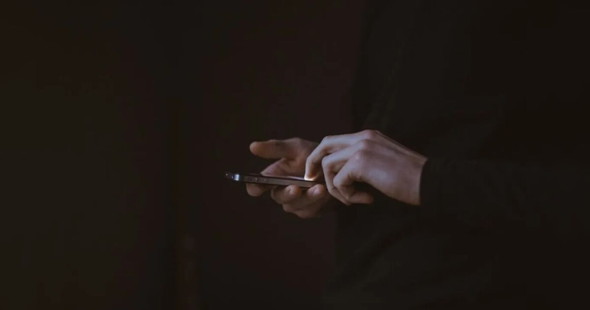 Homem usando celular com mensagem de aplicativo de mensagens aberta