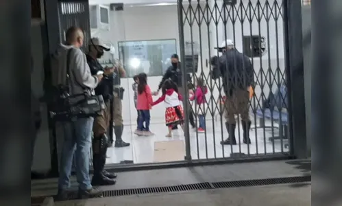 Crianças brincam com policiais enquanto pais são presos