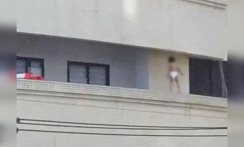 Criança se apoia em tela de sacada de prédio; vídeo