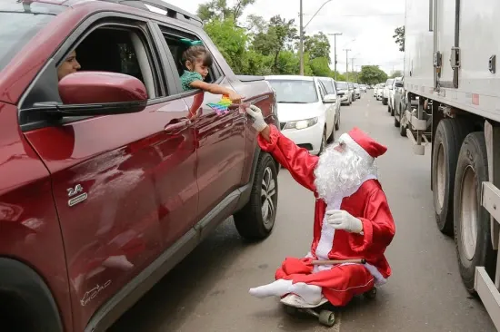 De skate, Papai Noel dribla carros e dificuldades na capital
