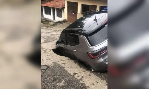 Asfalto cede e carro com família cai dentro de cratera