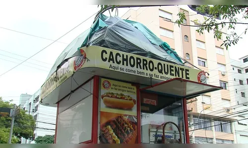 Homem improvisa barraca e dorme sobre quiosque de lanche