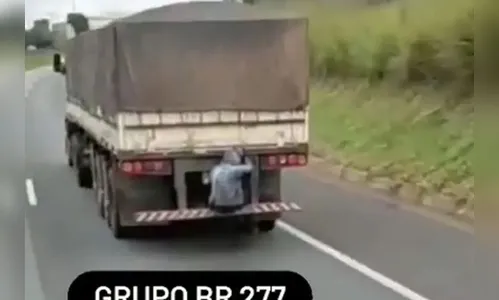 Passageiro é flagrado sentado em para-choque de caminhão
