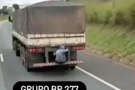 Passageiro é flagrado sentado em para-choque de caminhão