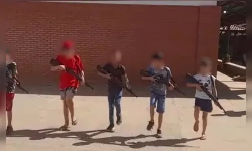 Crianças marcham e empunham réplicas de armas dentro de escola