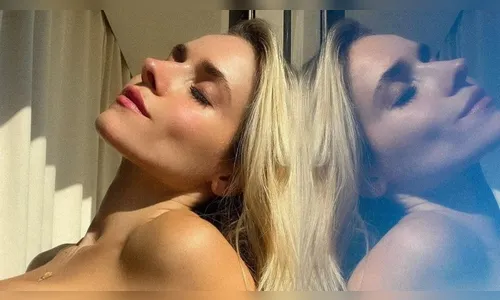 Monique Alfradique surge de biquíni tomara que caia em janela de casa