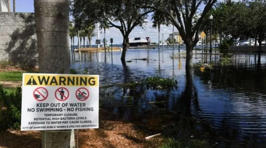 Aviso de alerta ao lado de área inundada após passagem do furacão Ian