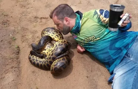 Cezar Augusto Arruda, aparece com um copo térmico na mão, se aproxima das cobras e beija cada uma delas