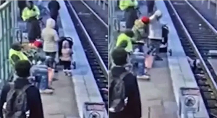 A menina estava com um casaco rosa e aguardando o trem com a sua mãe