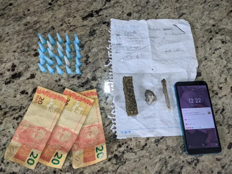 Porções de drogas, dinheiro e celular foram apreendidos
