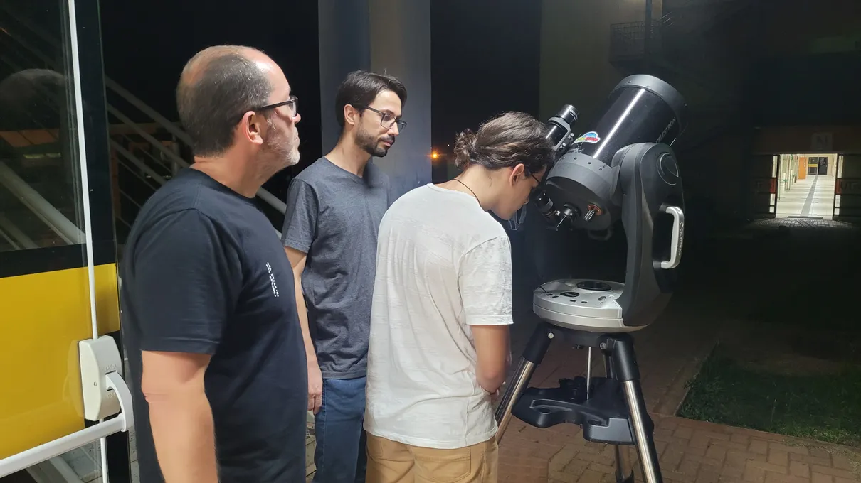 Professores e aluno observando pelo telescópio