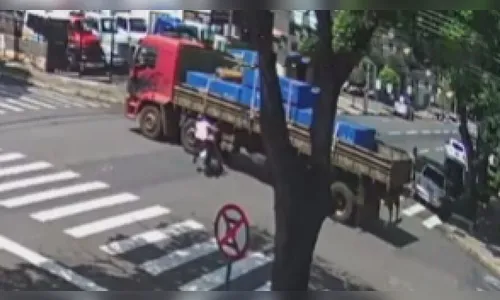 Mulher bate moto em caminhão e escapa de ser esmagada por um triz