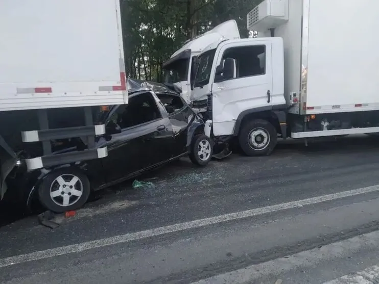 Um carro de passeio foi prensado por dois caminhões