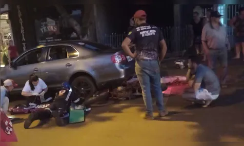 Motociclista vai parar embaixo de carro estacionado após colisão