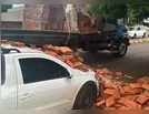 Caminhão carregado com tijolos derruba carga em picape estacionada