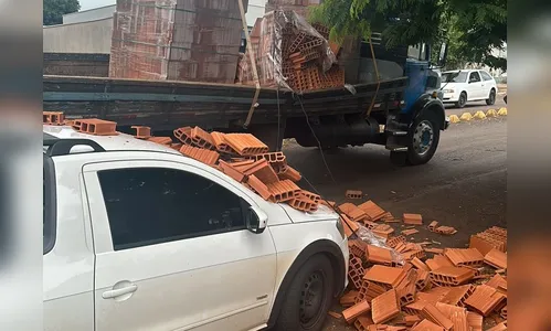 Caminhão carregado com tijolos derruba carga em picape estacionada