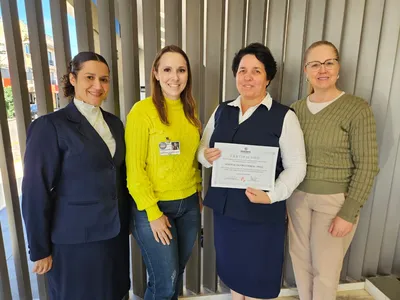 Irmã Geovana Ramos, diretora do hospital, mostra o certificado ao lado da equipe