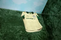 A camisa tem uma base dourada, com folhas como "marca d'água" tanto na parte superior quanto na inferior