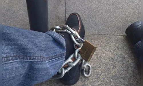 
							Dono de bar se acorrenta na frente de agência bancária para protestar
						
						