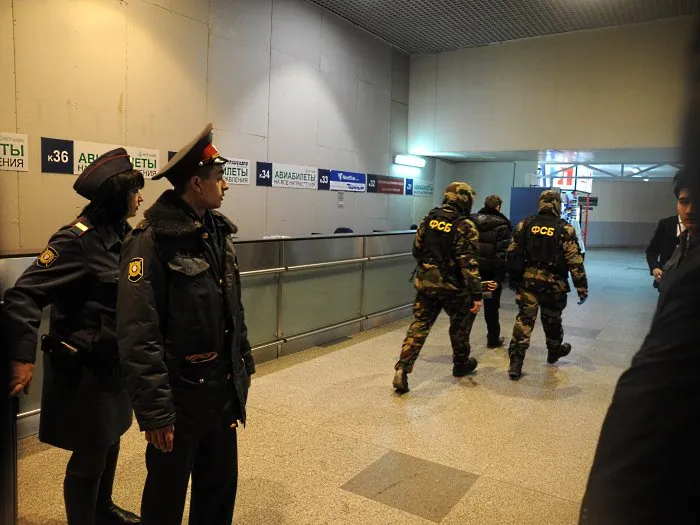  Policiais observam agentes da FSB em direção a terminal do aeroporto russo de Domodedovo