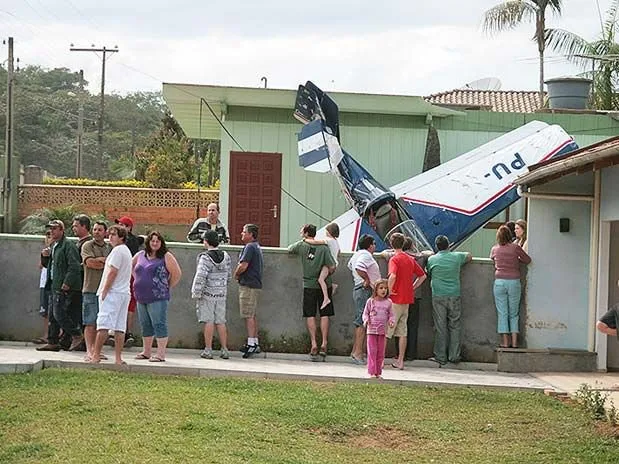  Moradores observam o pequeno avião que caiu no pátio de uma casa em Blumenau, sem deixar feridos