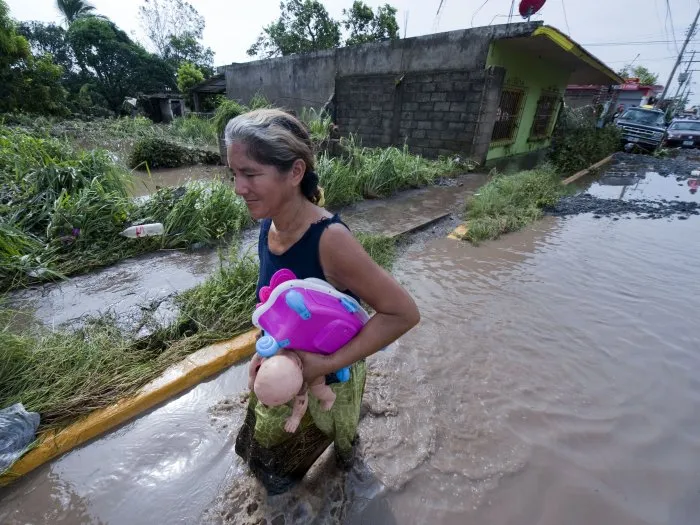  Residente de Cardel, em Veracruz, recolhe suas coisas e anda por rua alagada após passagem do furacão Karl na região