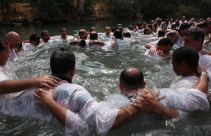  Peregrinos se banham no rio Jordão durante cerimônia de batismo com grupo de brasileiros