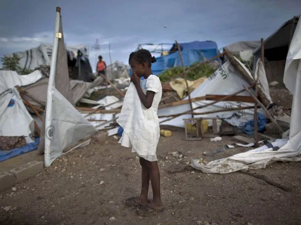  Menina em campo de sobreviventes de terremotos observa, neste sábado (25), os efeitos da chuva em Porto Príncipe
