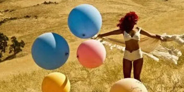 Cantora aparece de calcinha e sutiã branco, com seu contrastante cabelo vermelho, em um gramado cheio de balões coloridos