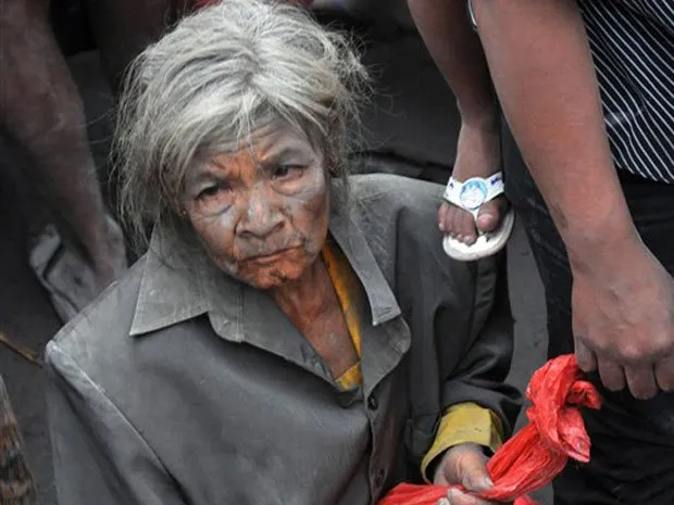  Coberta de cinza, mulher é retirada de área próximo à localidade indonésia de Argomulyo nesta sexta-feira (5) por conta da erupção do vulcão Merapi