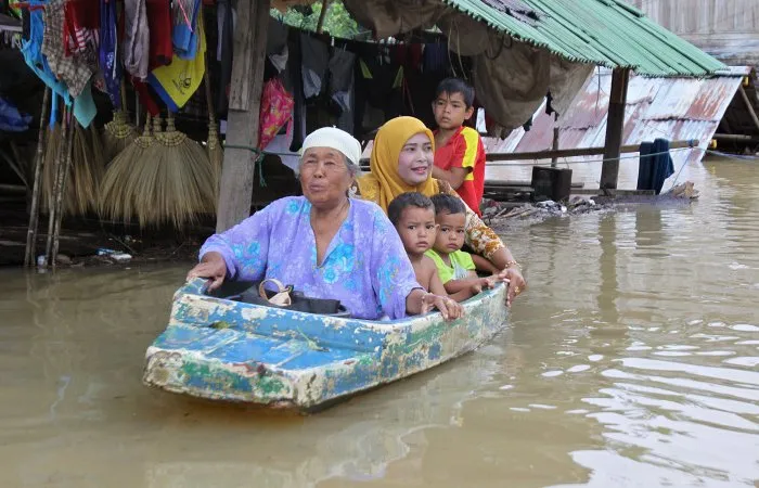  Família usa barco para de deslocar em meio à inundação na cidade de Pattani, na Tailândia, nesta sexta-feira (5)