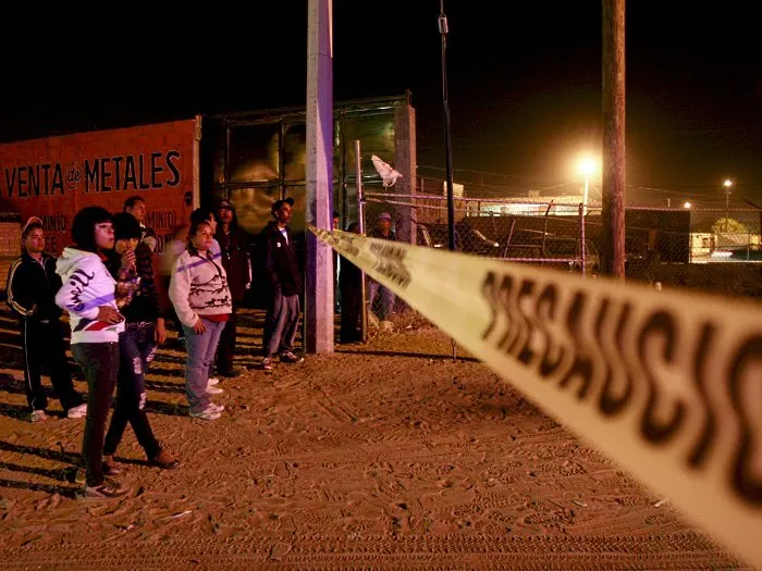  Jovens observam área isolada pela polícia para examinar cena de crime em Ciudad Juárez