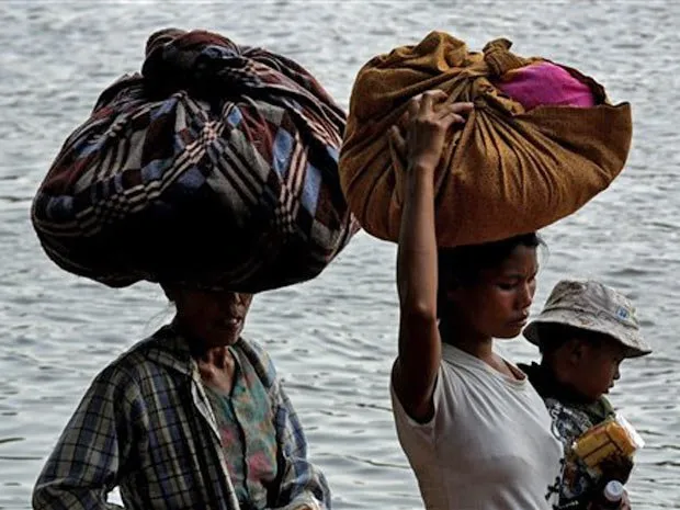  Refugiadas de Mianmar carregam sacolas na cabeça ao cruzar a fronteira 