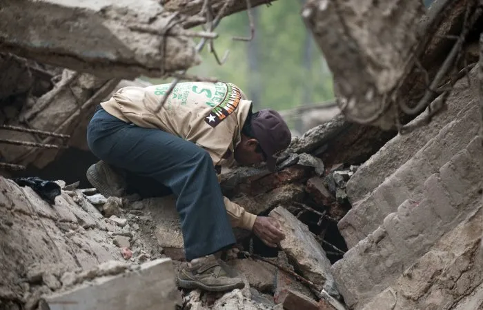  Membro de equipe de resgate procura por sobrevivente após desabamento de prédio em Nova Déli, na Índia