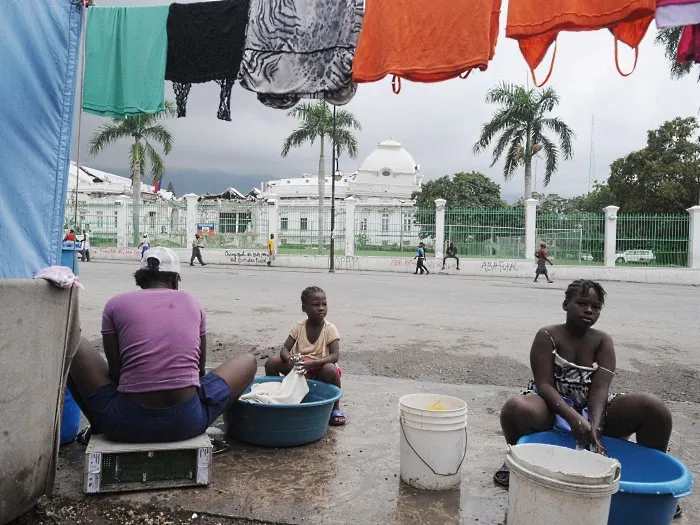  Mulheres lavam roupa em frente aos escombros do palácio presidencial do Haiti, ainda em ruínas um ano após o terremoto
