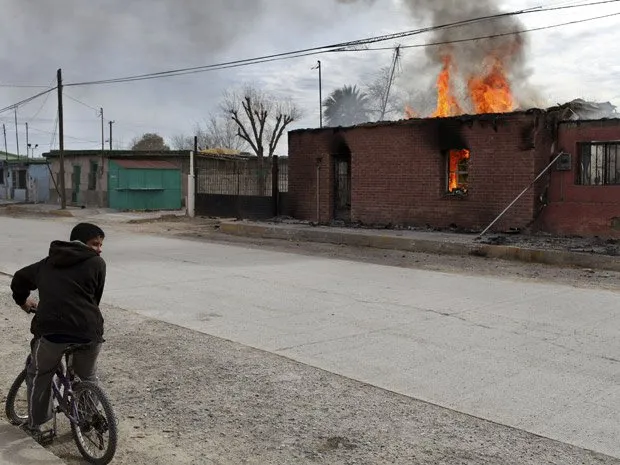  Garoto para a bicicleta para observar casa pegando fogo em Guadalupe. Disputas entre traficantes fazem famílias abandonarem tudo em busca de lugar mais seguro
