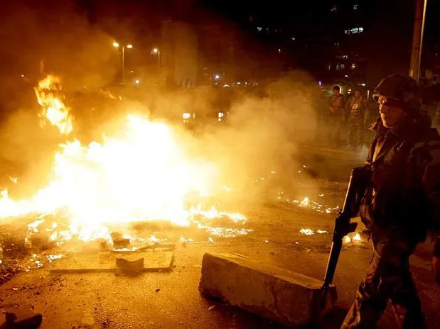  Soldado libanês observa pneus em chamas depois de manifestantes sunitas atearem fogo perto da estrada do aeroporto em Beirute
