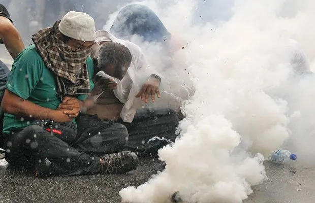  Membros da Coalizão por Eleições Limpas e Justas se protegem das bombas de gás atiradas pela polícia em Kuala Lumpur