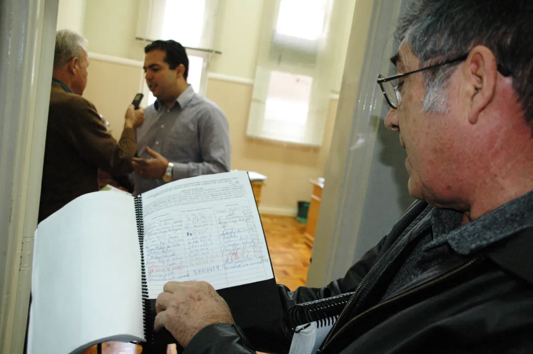 O presidente do OSA, Mauro de Oliveira Carlos, mostra o abaixo-assinado apresentado ao presidente da Câmara, Alcides Ramos (dando entrevista, ao fundo) 