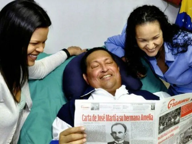 Acompanhado de suas filhas o presidente da Venezuela sorri enquanto lê o jornal