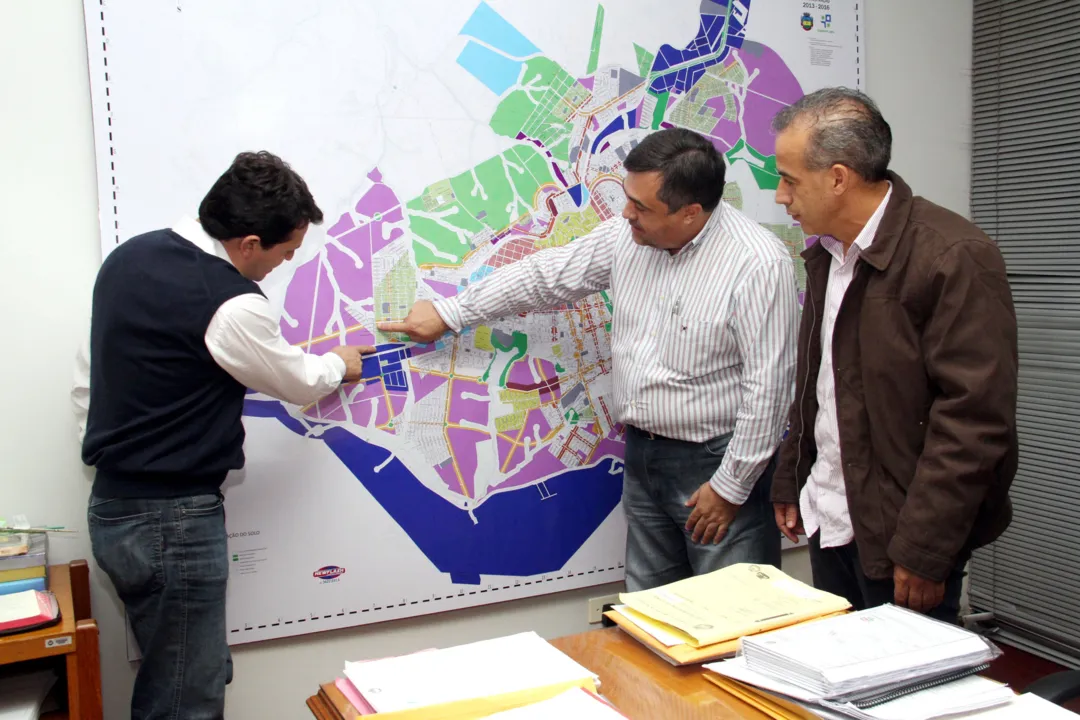 Beto Preto, Val e Junior observam no mapa da cidade o local onde será construído o pontilhão (Foto - Josias Profeta)