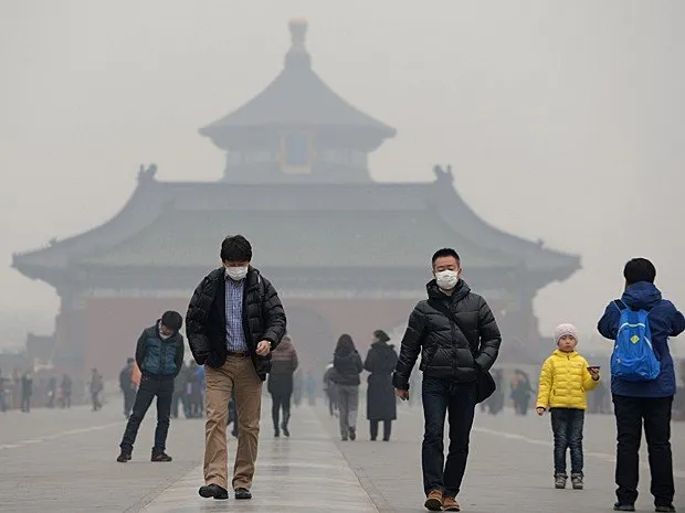  Visitantes usam máscaras enquanto visitam o Templo do Céu, em Pequim. (Foto: China Out/AFP)