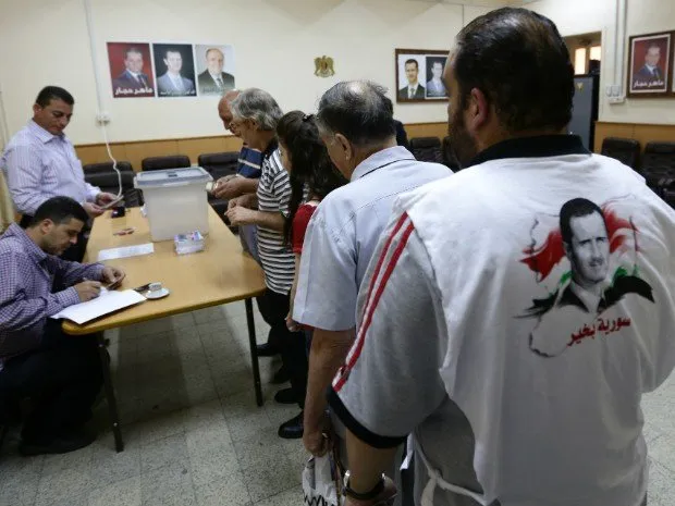  Sírios fazem fila em local de votação no centro de Damasco nesta terça-feira (3) (Foto: Louai Beshara/AFP)