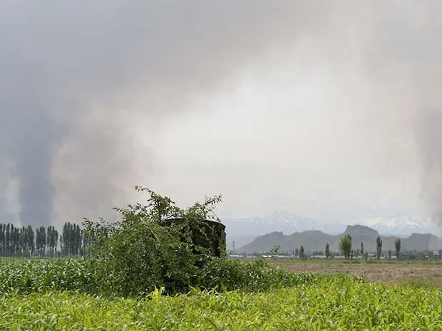  Fumaça é vista após ataque a casas de uzbeques em vilarejo perto de Osh, no Quirguistão 