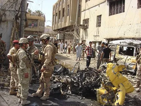  Policiais iraquianos observam carro bomba destruído no Distrito de Hurriya, em Bagdá; 64 pessoas morreram por carros-bomba na capital do país