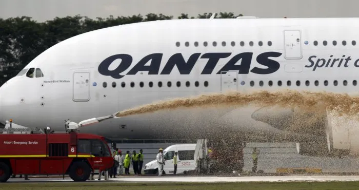  Equipes de emergência jogam espuma sobre motor do Airbus A380 da Qantas que fez pouso de emergência em Cingapura