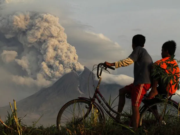  Crianças de bicicleta observam vulcão Merapi em atividade, na Indonésia 