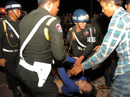  Policiais e militares carregam um corpo perto da ponte em Phnom Penh, onde um festival anual acabou em tragédia no Camboja