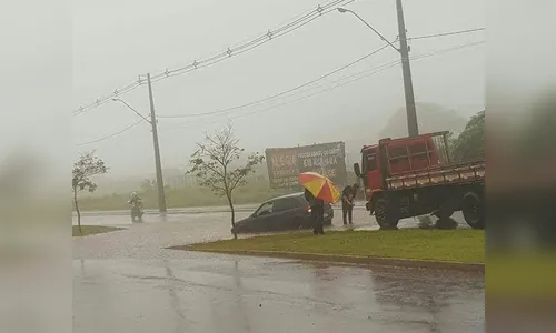 Carro fica preso em buraco ao tentar passar em rua alagada 